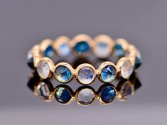 Lovely blue sapphire and moonstones are set in 18k gold. A delightful pattern this makes a great stacking ring. Moonstones and sapphires are alternated in a clean simple style which makes this really special.  Stunning and gorgeous, this will make a delightful wedding band for a bride who has a September birthday or is simply captivated by the mesmerizing blue of a sapphire. Minimalist in style this makes a great option. Can also be made with other stones like rubies and emeralds. Please convo m Luxury Blue Moonstone Ring Gift, Sapphire Moonstone Gemstone Ring, Luxury Blue Moonstone Wedding Ring, Luxury Blue Moonstone Ring, Blue Multi-stone Moonstone Ring, Celestial Blue Round Moonstone Ring, Celestial Blue Moonstone Ring, Blue Round Stackable Moonstone Ring, Blue Moonstone Round Ring Fine Jewelry