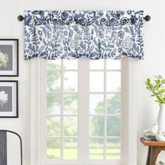 the window is decorated with blue and white flowers on it's valance, along with two framed pictures