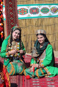 two women in traditional clothing sitting on a rug