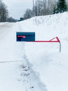 a mailbox sitting on the side of a snow covered road next to a forest