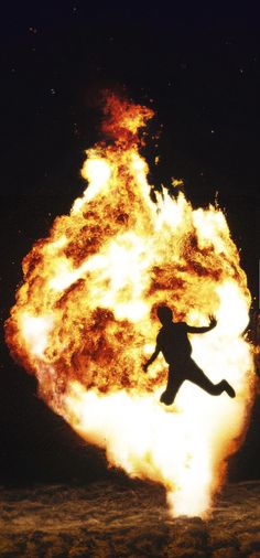 a person jumping in front of a large fireball