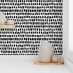 black and white wallpaper in a kitchen with two vases next to each other