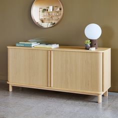 a sideboard with a mirror on the wall above it and bookshelf behind it