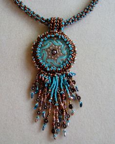 a beaded necklace with an intricate design on the front and back end, hanging from a chain