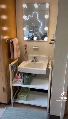 a bathroom with a sink, mirror and towel rack in it's corner next to a door