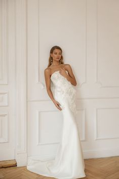 a woman in a white wedding dress posing for the camera with her hand on her hip