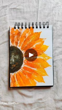 an orange and yellow sunflower painted on a notebook