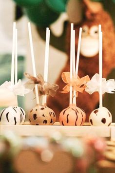 several cake pops with bows on them sitting in front of a teddy bear and other decorations