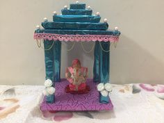 an elephant statue sitting on top of a purple and blue stand with pearls hanging from it's sides