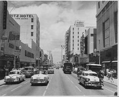 an old black and white photo of cars driving down the street