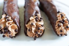 three chocolate covered donuts on a white plate