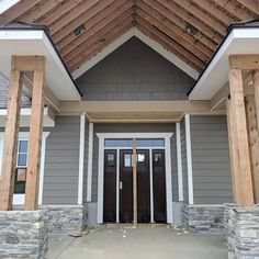 the front entrance to a house with stone pillars and wood trimmings on it