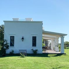 a small white house sitting on top of a lush green field