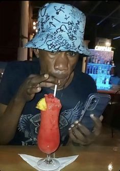 a man sitting at a table with a drink and cell phone in front of him