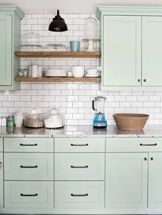 a kitchen with green cabinets and white subway backsplash