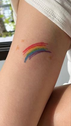 a woman's arm with a rainbow tattoo on the left side of her leg