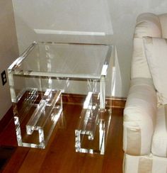 two clear acrylic tables sitting on top of a wooden floor next to a couch