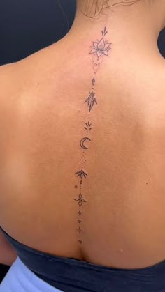 the back of a woman's neck with an arrow and moon tattoo on it