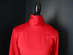 "Vintage red professional blouse from JH Collectibles. Long sleeves with thick button cuff at wrist, and buttons up back of high neck collar. Waist is tailored and defined. Padded shoulders. 100% Polyester Size 8. 20\" underarm to underarm 24\" sleeve 25.5\" length." Formal High Neck Fitted Blouse, Fitted Turtleneck Blouse For Work, Formal Solid Tops For Winter, Red Fitted Top For Formal Occasions, Formal Stretch Winter Tops, Fitted Solid Tops With Stand Collar, Fitted Solid Color Top With Stand Collar, Fitted High Neck Blouse, Formal Winter Fitted Top