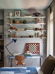 a bedroom with shelves and a desk in the corner next to a window that has a checkered rug on it