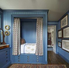 a bedroom with blue walls and wooden flooring has a canopy bed in the middle