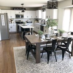 a dining room table with four chairs and a rug on the floor in front of it