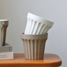 two white vases sitting next to each other on a wooden table with a book