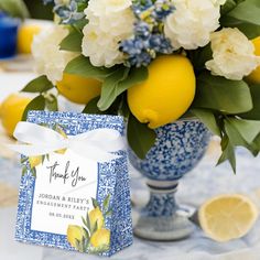 a blue and white vase filled with lemons next to a small thank you card