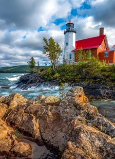 a red and white lighthouse sitting on top of a rocky shore