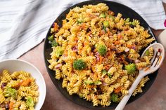 a bowl full of pasta with broccoli and other food items next to it