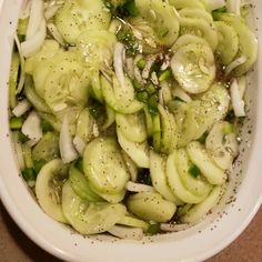 a white bowl filled with sliced cucumbers and onions on top of a table