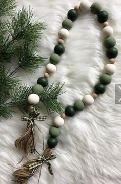 a green and white beaded necklace sitting on top of a furnishing next to a pine tree