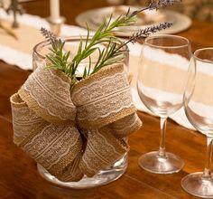 two wine glasses are sitting on a table with a burlock bow tied around it