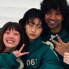 three people posing for the camera with their hands in the shape of two peace signs