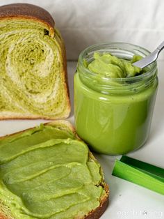 there is a sandwich with avocado on it next to a jar of pickles