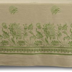 an embroidered tablecloth with green flowers and leaves on the border, in front of a white background