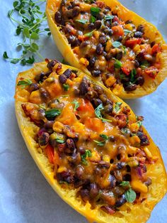 two stuffed squash halves with black beans and cheese on top, garnished with fresh herbs