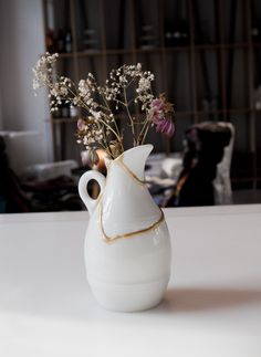 a white vase filled with flowers on top of a table