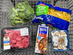 some food is sitting on top of a wire rack in a grocery cart, including broccoli and other foods