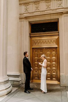 a man and woman standing in front of a wooden door