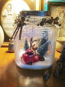 a glass jar filled with snow and a red truck on top of a wooden table