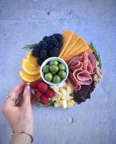 a platter with cheese, meats, fruit and vegetables is shown in the shape of a circle