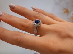 a woman's hand with a diamond and blue sapphire ring on her left hand