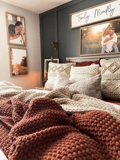 a bed with blankets, pillows and pictures on the wall above it in a bedroom