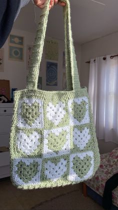 a person holding up a crocheted bag in their hand with the handles down