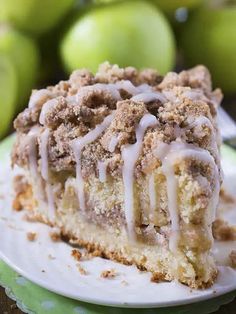 a close up of a slice of cake on a plate with apples in the background