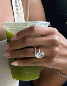 a close up of a person holding a drink with a diamond ring on it's finger