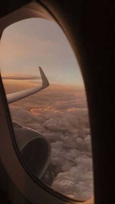 an airplane window looking out at the clouds and sky from inside another plane's wing