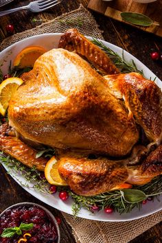 a turkey on a platter with oranges, cranberries and other holiday foods