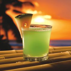 a green drink sitting on top of a bamboo table